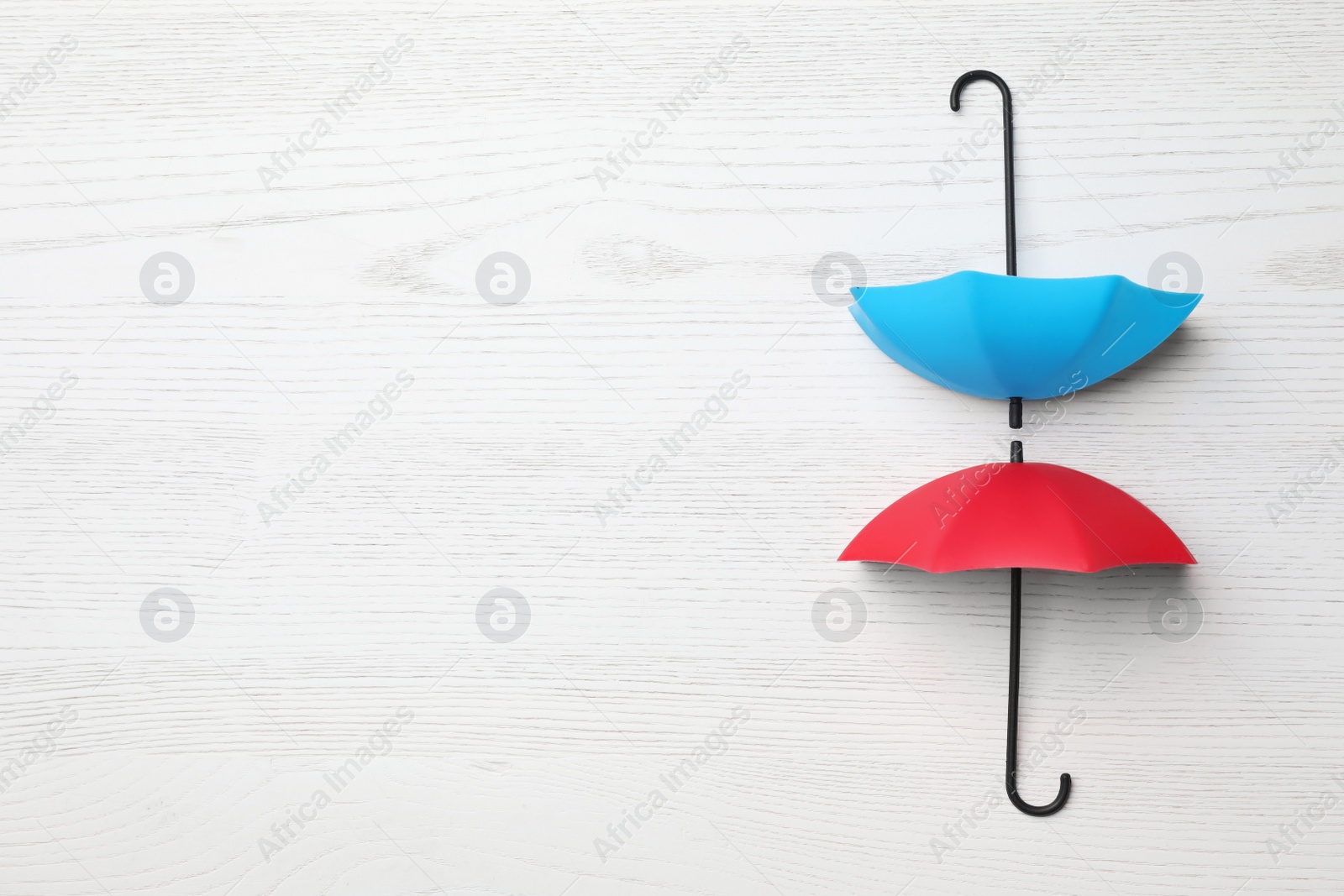 Photo of Small color umbrellas on white wooden background, flat lay. Space for text
