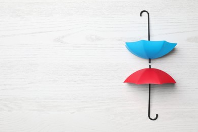 Small color umbrellas on white wooden background, flat lay. Space for text