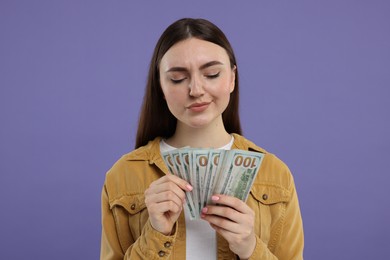 Woman with dollar banknotes on purple background