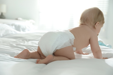 Photo of Cute little baby in diaper on bed at home