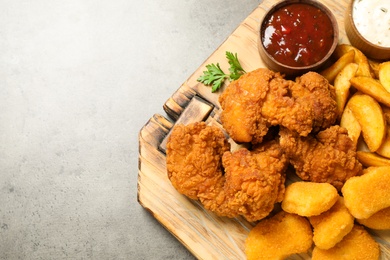 Tasty fried chicken nuggets served on grey table, top view. Space for text