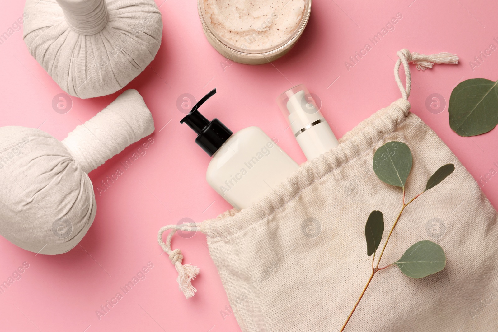 Photo of Preparation for spa. Compact toiletry bag with different cosmetic products, herbal bags and eucalyptus on pink background, flat lay