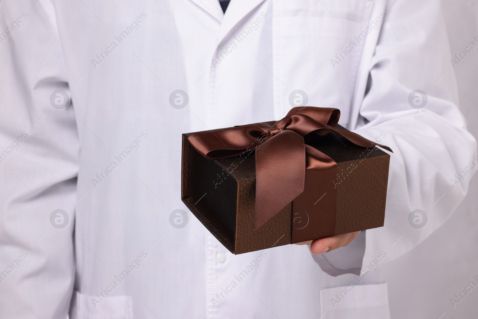 Photo of Doctor holding gift box on white background, closeup. Medical present