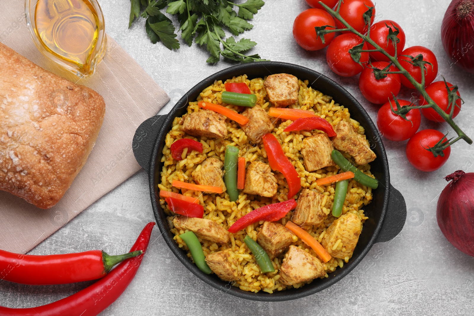 Photo of Delicious rice and chicken served with vegetables on light grey table, flat lay