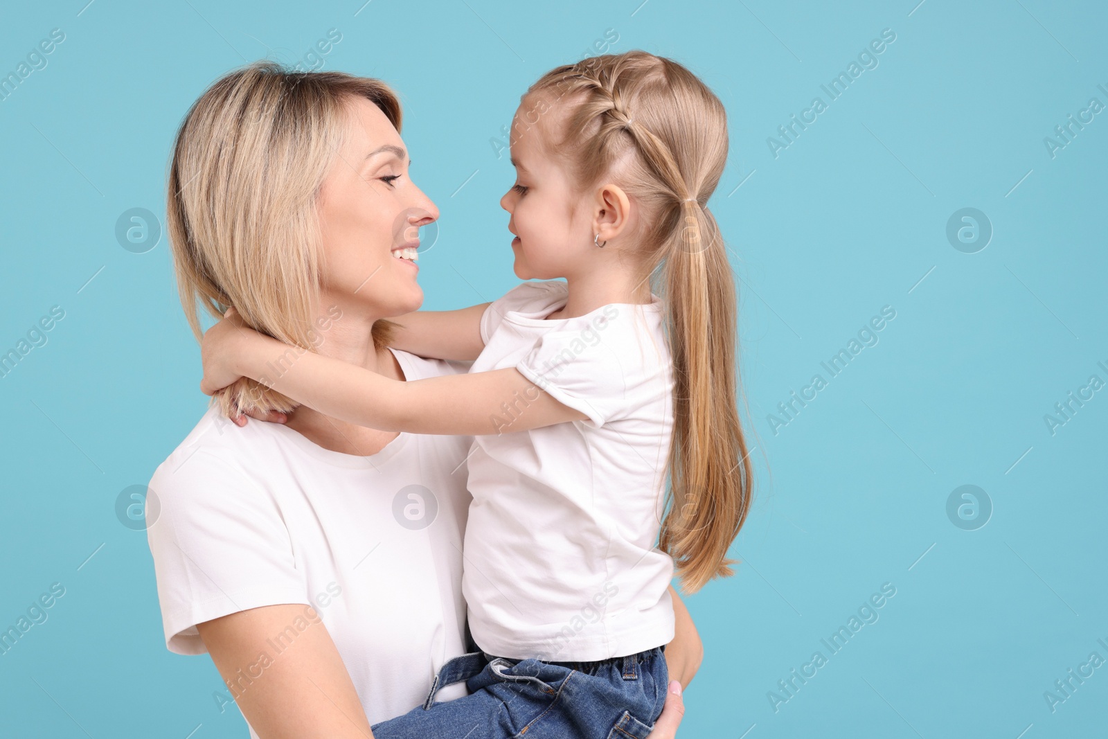 Photo of Family portrait of happy mother and daughter on light blue background. Space for text