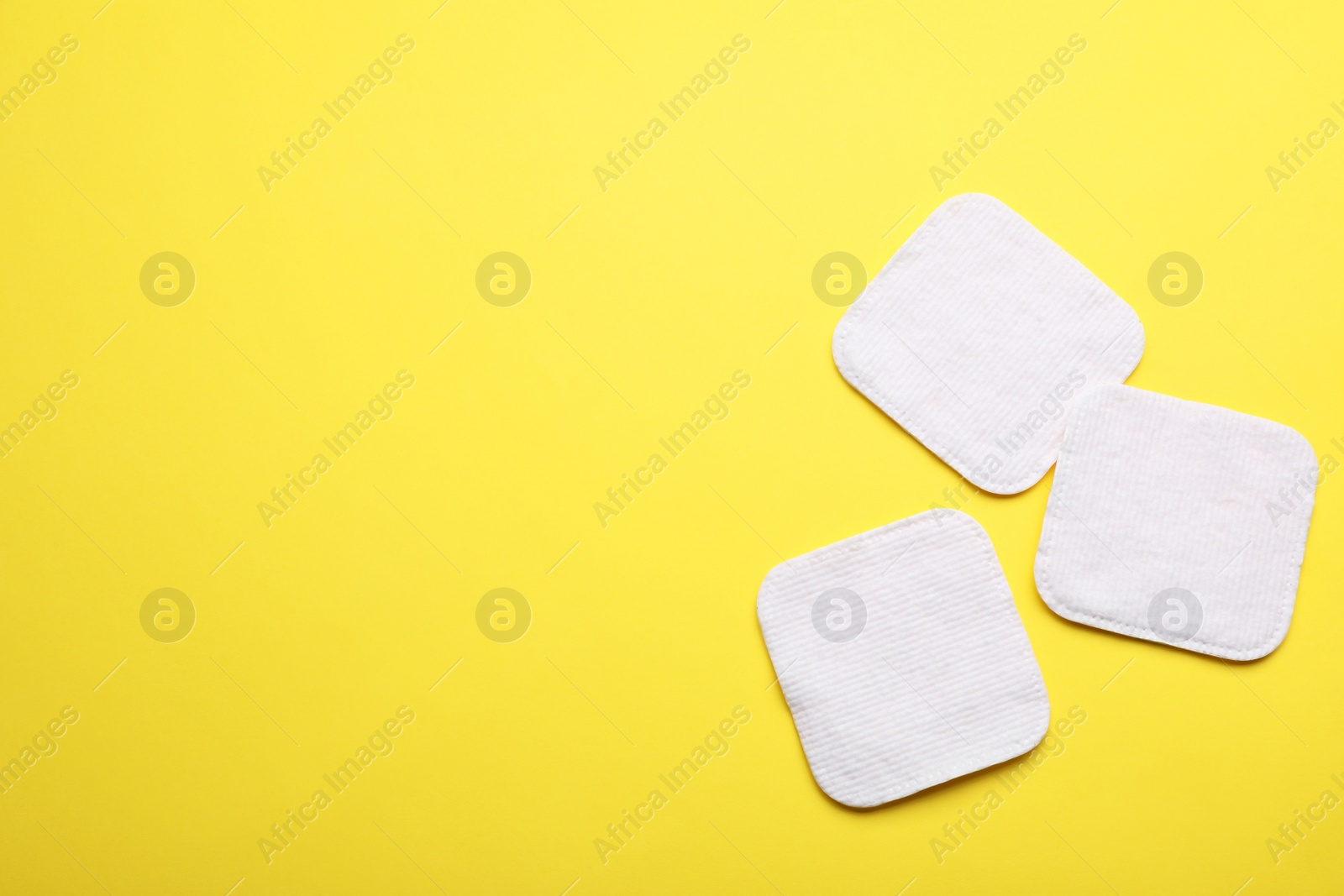 Photo of Soft clean cotton pads on yellow background, flat lay. Space for text