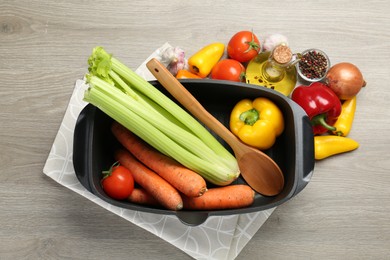 Photo of Black pot, spoon and fresh products on wooden table, top view