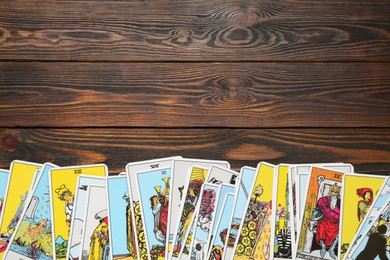 Photo of Tarot cards on wooden table, top view. Space for text