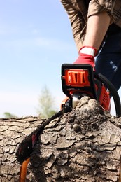 Man sawing wooden log outdoors, closeup view