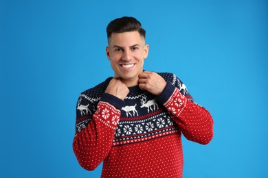 Handsome man in Christmas sweater on blue background