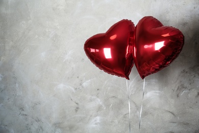 Red heart shaped balloons near grey wall, space for text. Valentine's Day celebration