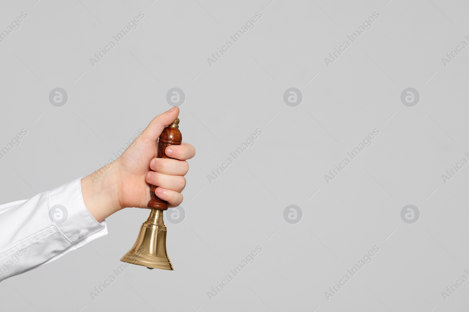 Photo of Pupil with school bell on light grey background, closeup. Space for text