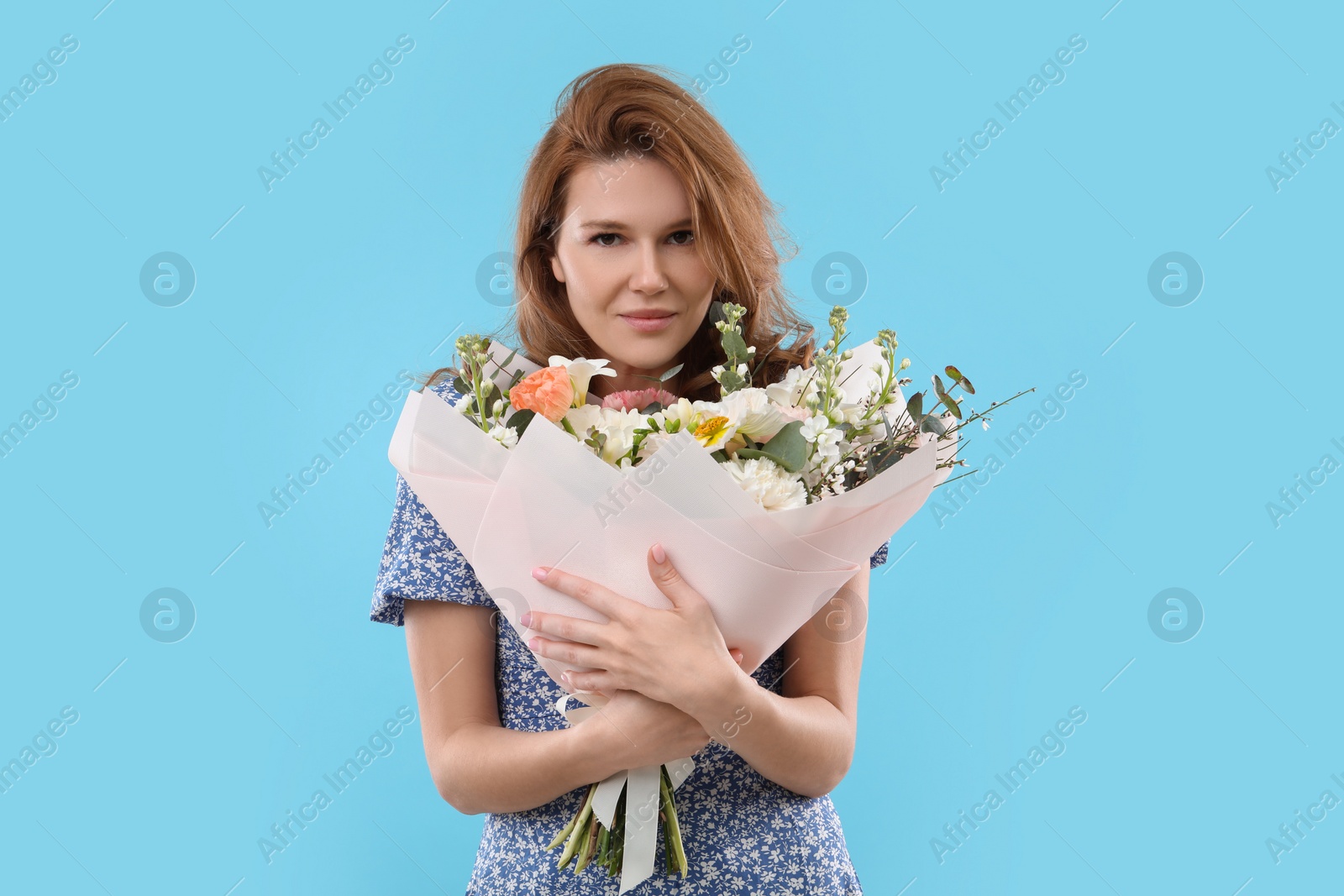 Photo of Beautiful woman with bouquet of flowers on light blue background