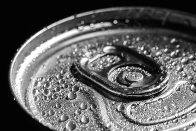 Photo of Aluminum can of beverage covered with water drops on black background, closeup