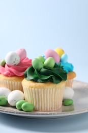 Tasty cupcakes with Easter decor on light blue background, closeup