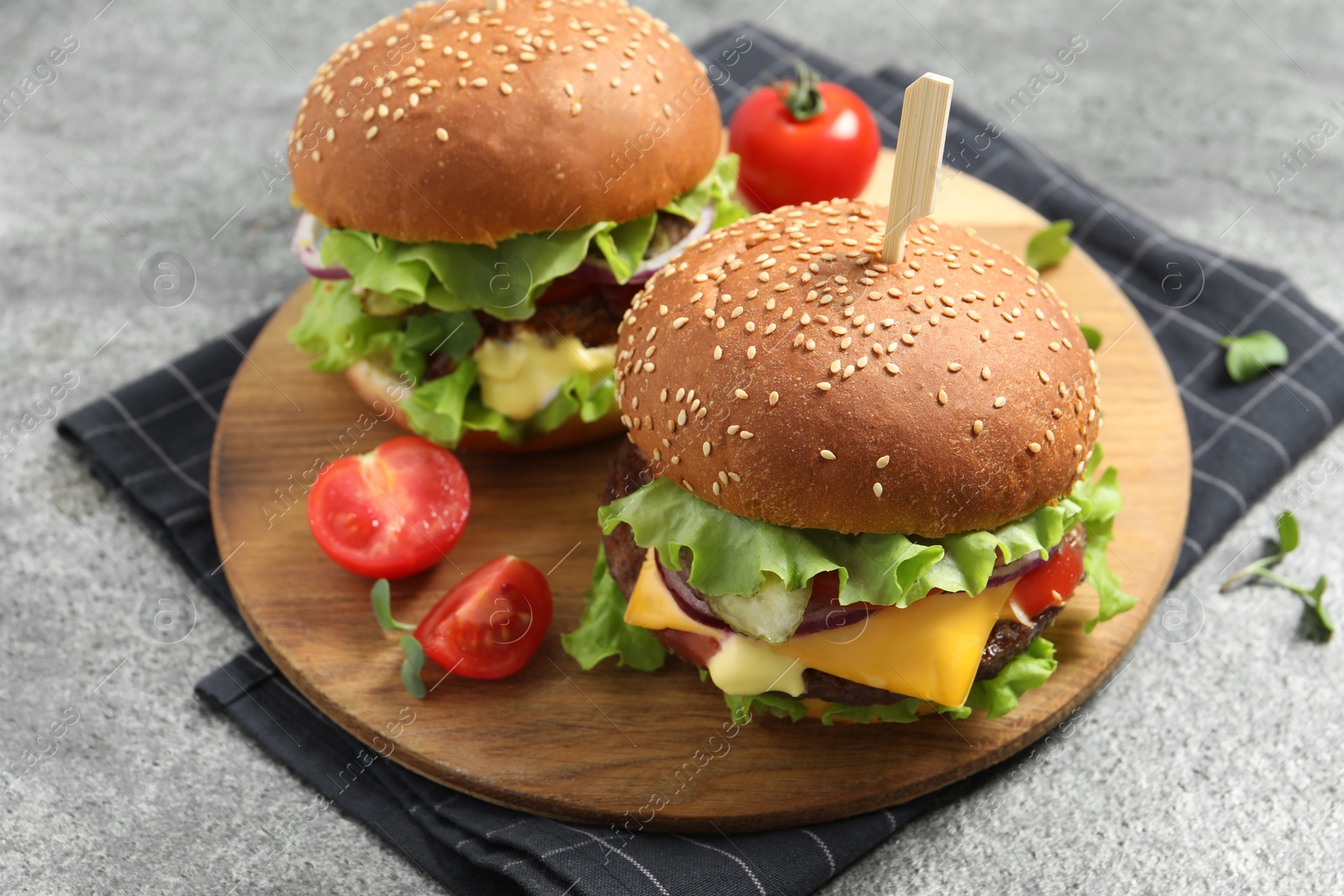 Photo of Delicious burgers with beef patty and tomatoes on grey table