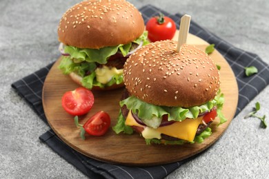 Delicious burgers with beef patty and tomatoes on grey table