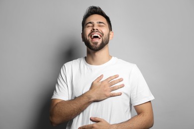 Photo of Young man laughing on light grey background. Funny joke