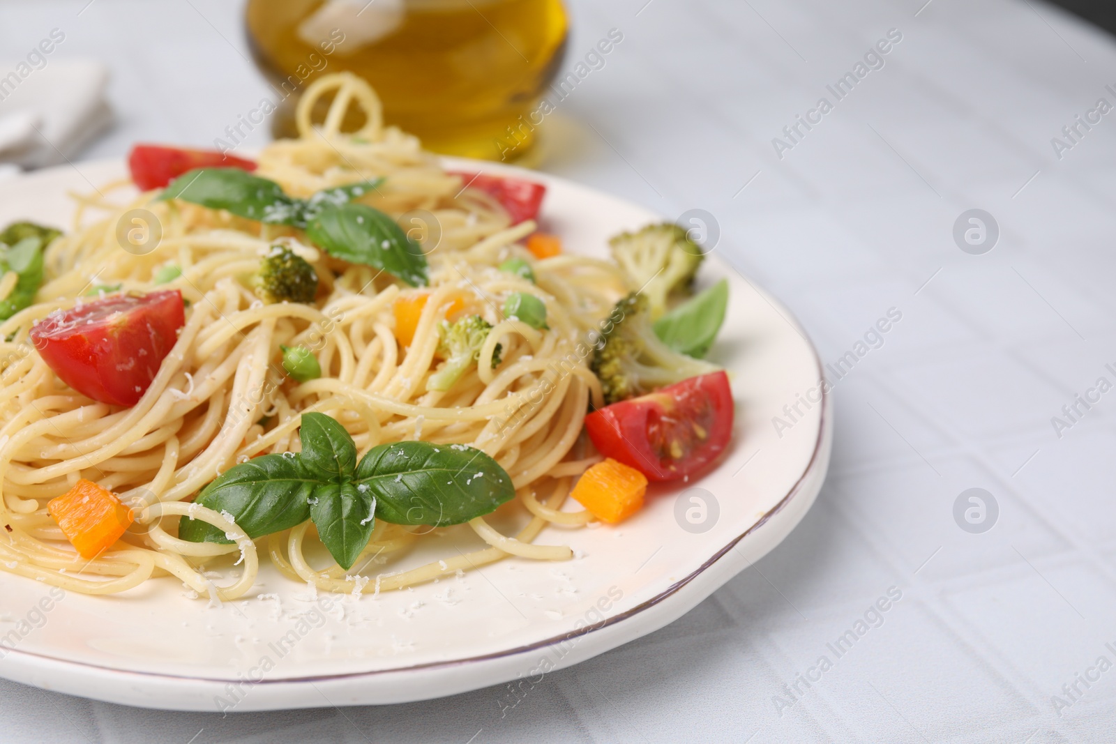 Photo of Delicious pasta primavera with tomatoes, basil and broccoli on white tiled table, closeup. Space for text