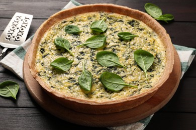 Photo of Delicious homemade spinach pie and spatula on wooden table