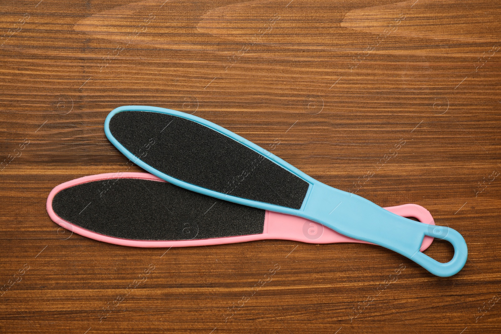 Photo of Colorful foot files on wooden table, flat lay. Pedicure tools