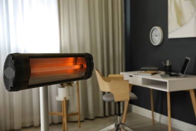 Photo of Modern electric infrared heater in room interior, closeup