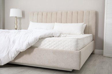 Comfortable bed with soft white mattress, blanket and pillows indoors