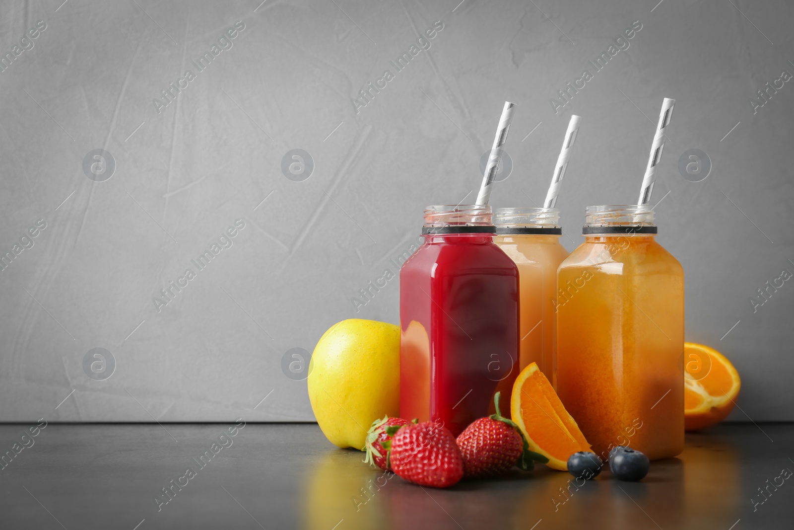 Photo of Bottles with healthy detox smoothies and ingredients on table