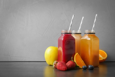 Photo of Bottles with healthy detox smoothies and ingredients on table