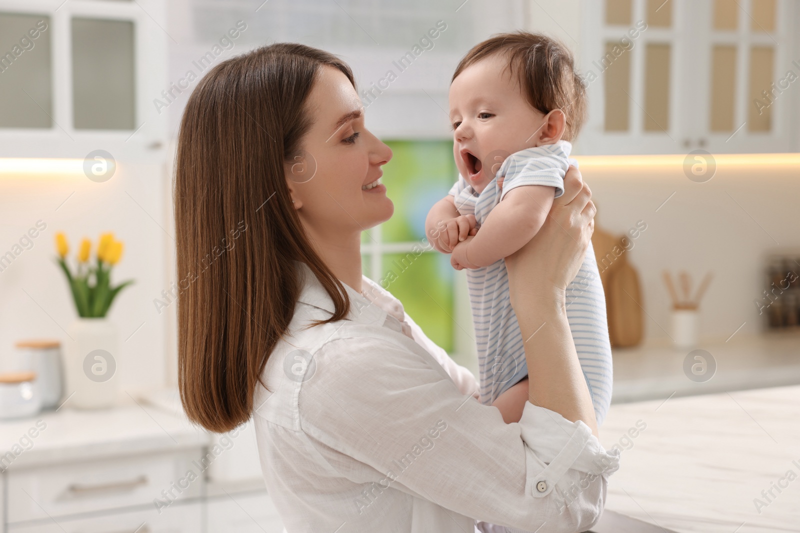 Photo of Happy mother with her little baby in kitchen at home