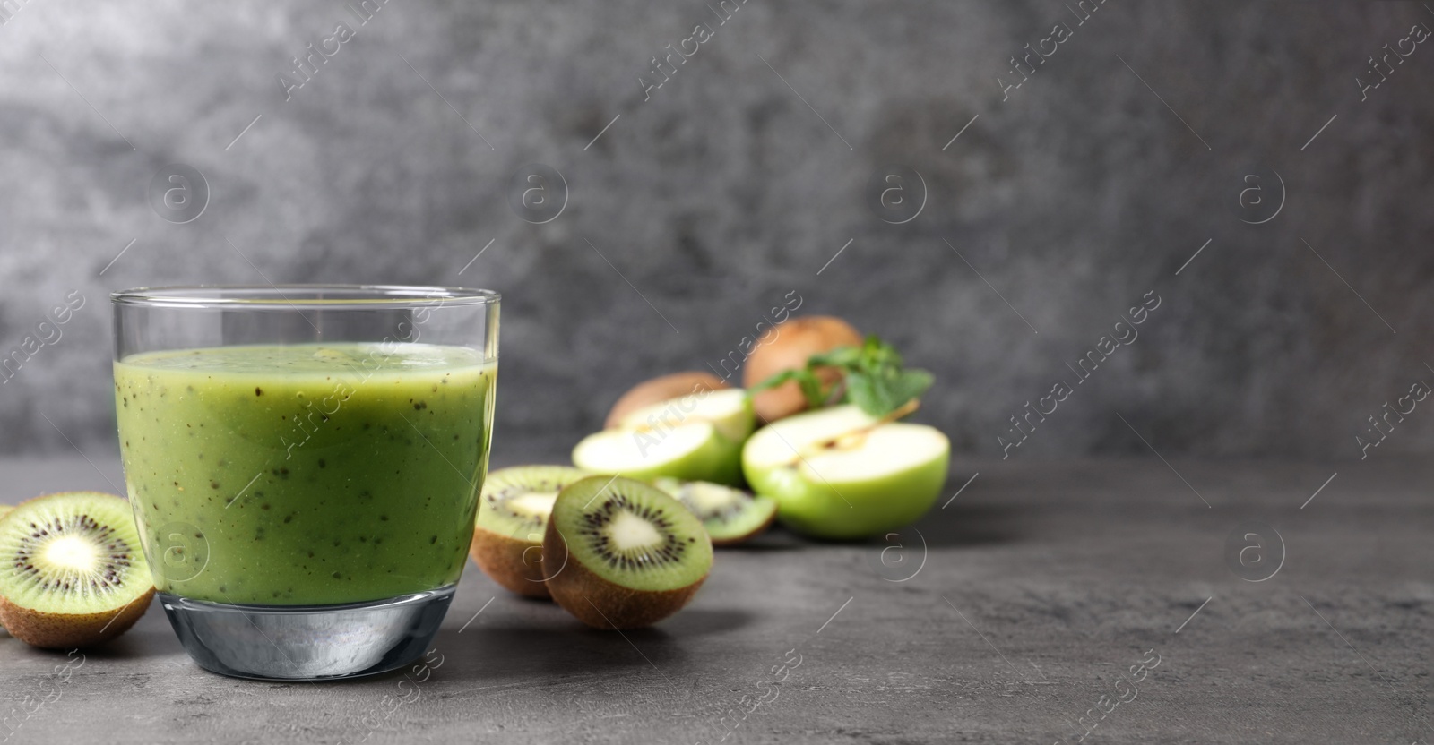 Photo of Delicious kiwi smoothie and fresh fruits on grey table. Space for text