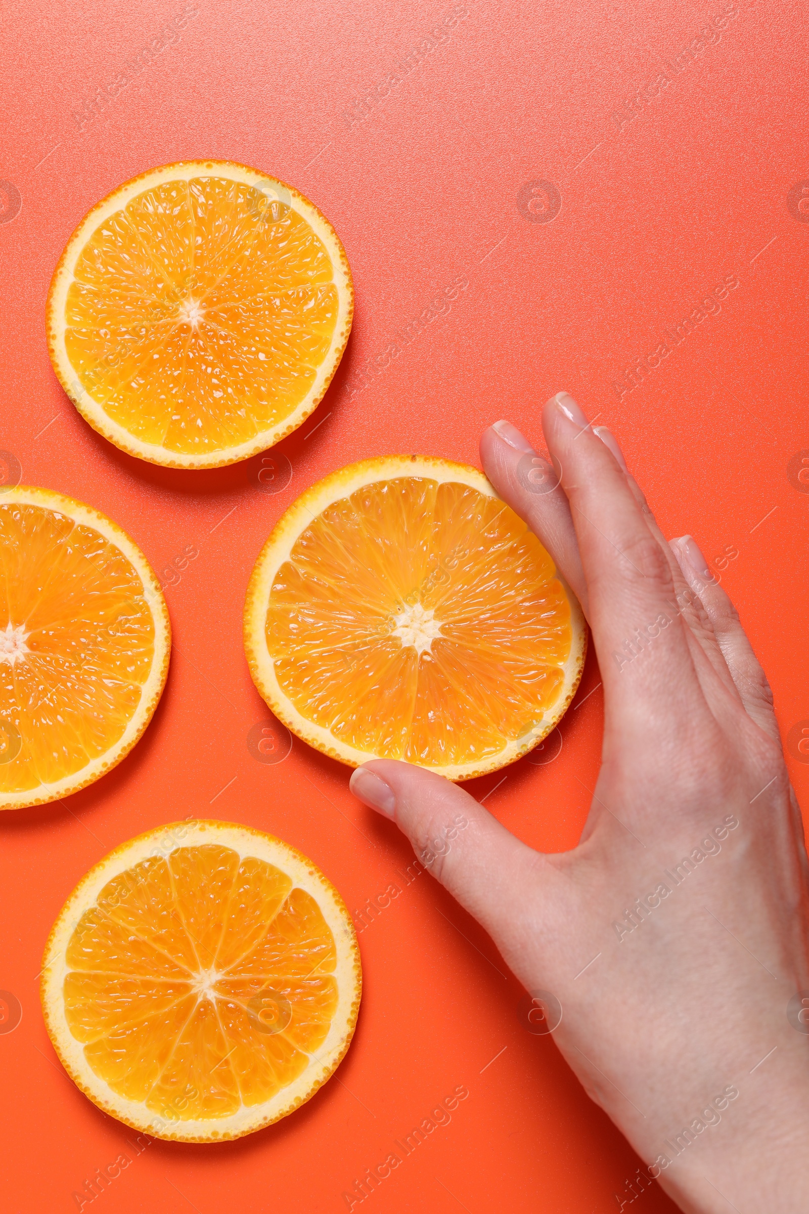 Photo of Woman with slices of juicy orange on terracotta background, top view