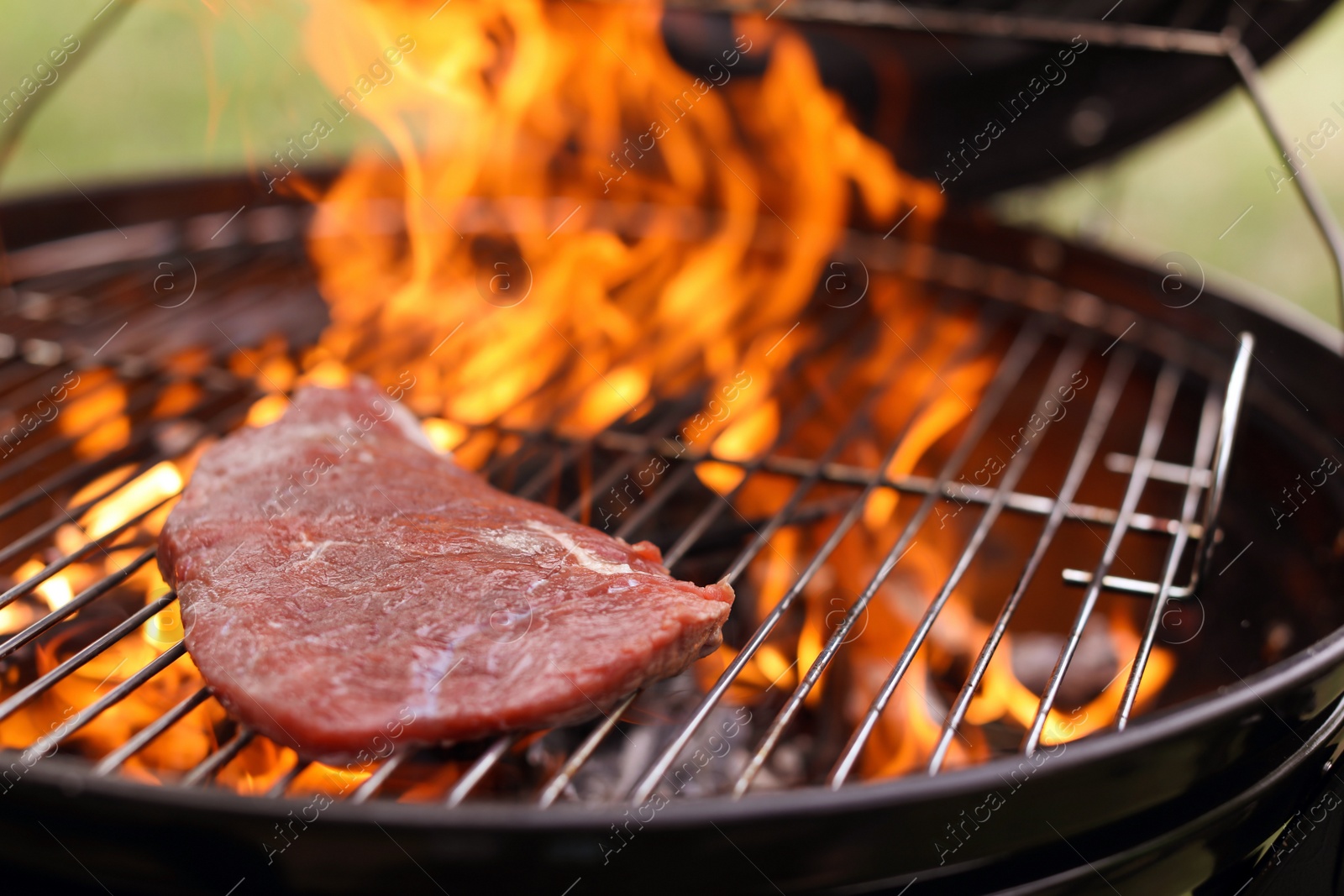 Photo of Tasty meat on barbecue grill with fire flames outdoors, closeup