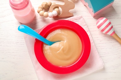 Photo of Flat lay composition with bowl of healthy baby food on white wooden table