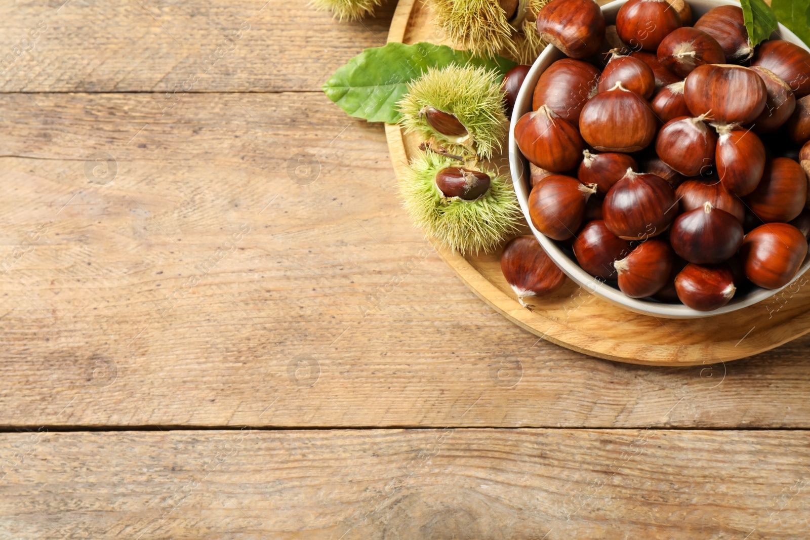 Photo of Fresh sweet edible chestnuts on wooden table, top view. Space for text