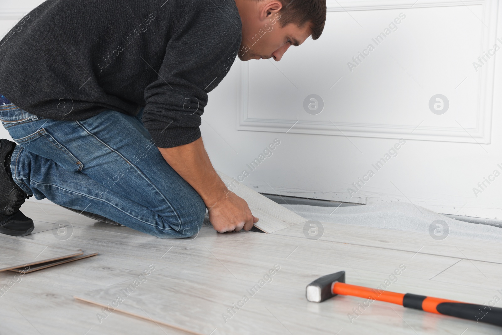 Photo of Worker installing new laminate flooring in room, closeup