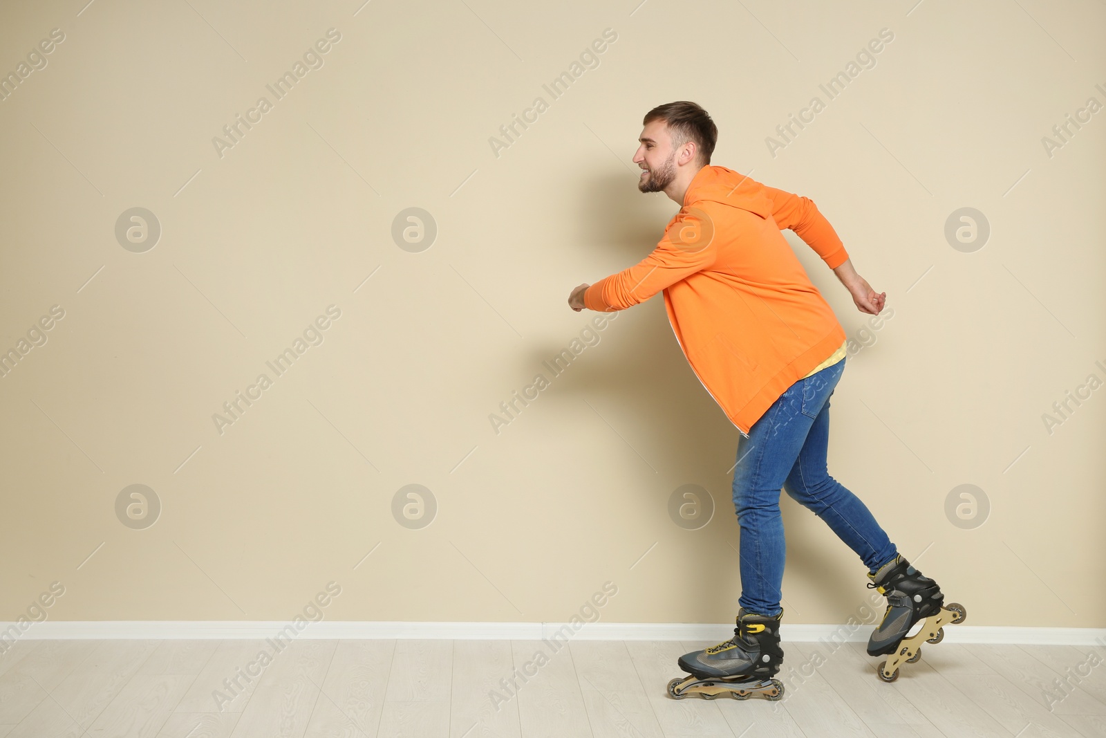 Photo of Young man with roller skates near color wall. Space for text