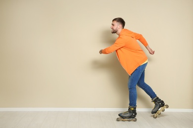 Photo of Young man with roller skates near color wall. Space for text