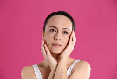 Portrait of beautiful mature woman on pink background