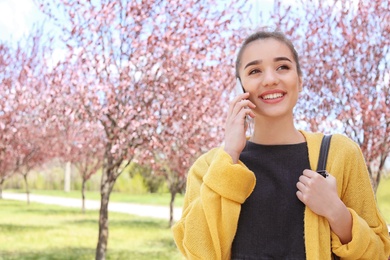 Photo of Young woman talking by phone outdoors on sunny day