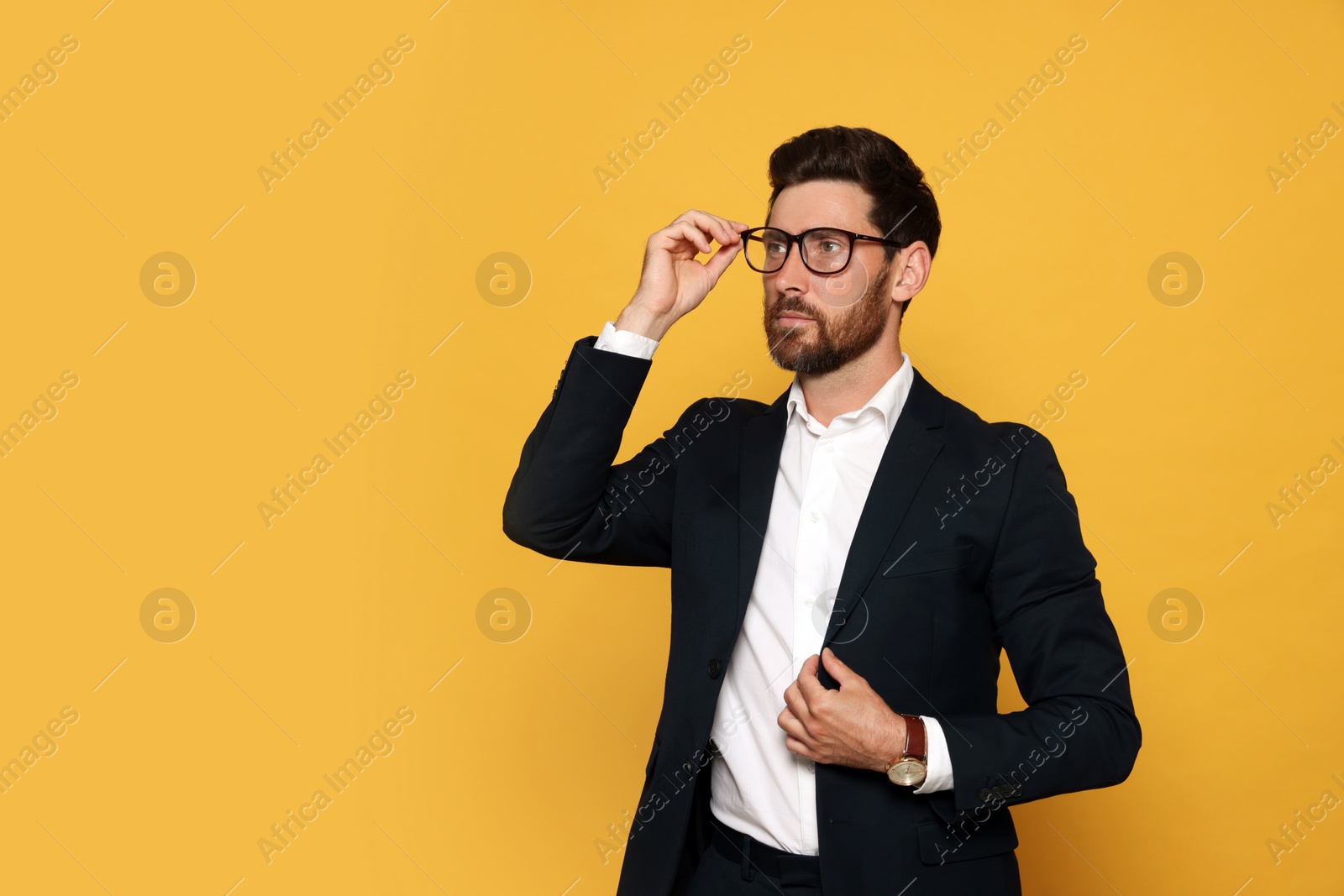 Photo of Portrait of bearded man with glasses on orange background. Space for text