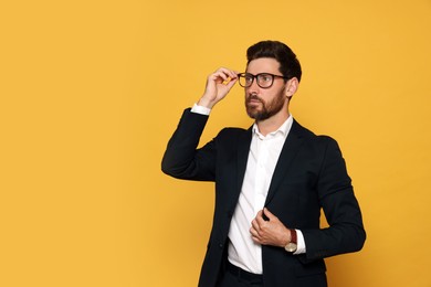 Photo of Portrait of bearded man with glasses on orange background. Space for text