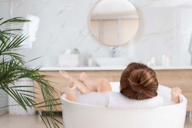 Photo of Woman enjoying bubble bath at home, back view