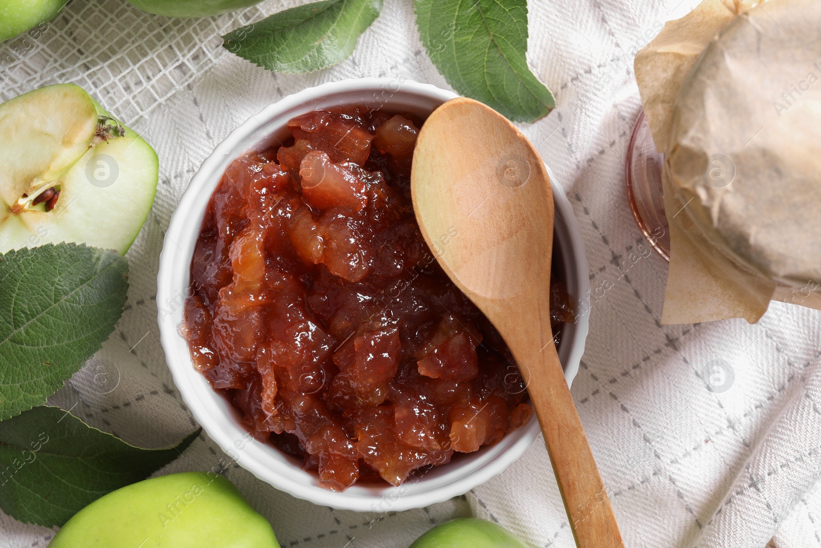 Photo of Bowl of delicious apple jam and fresh fruits on white tablecloth, flat lay