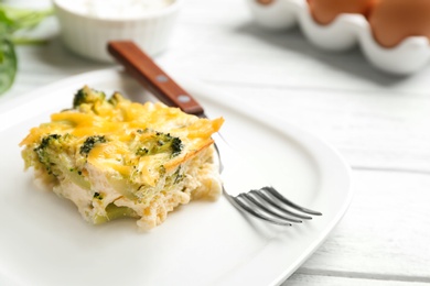 Photo of Piece of tasty broccoli casserole on white wooden table