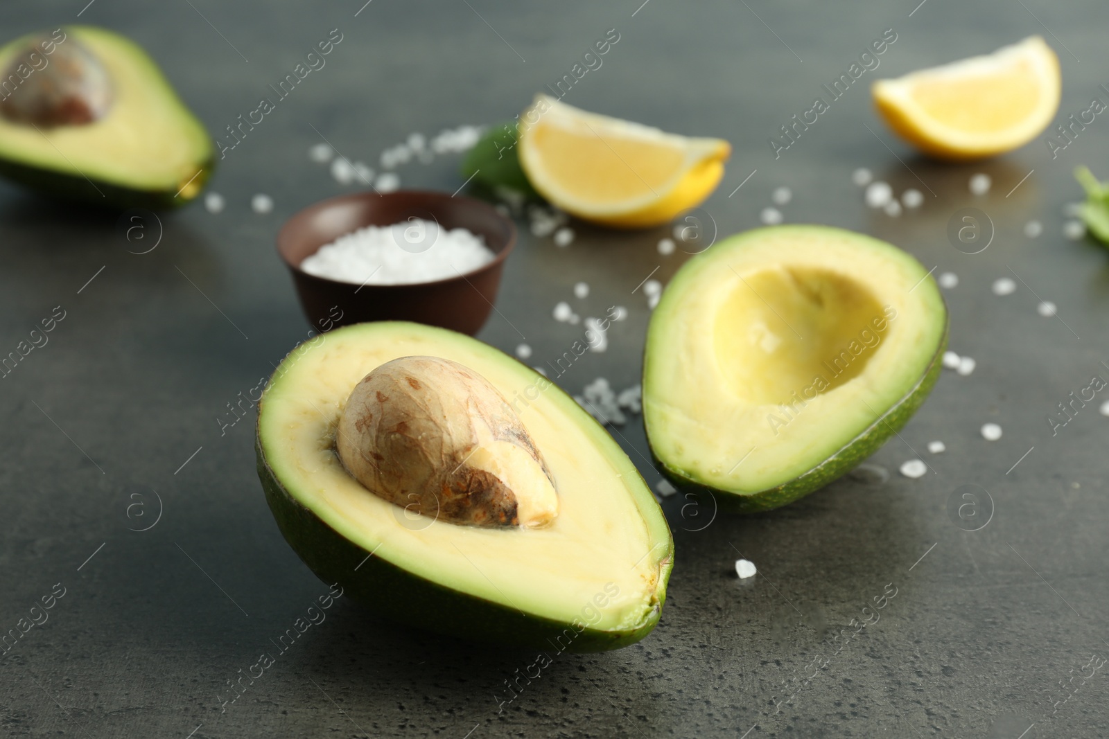 Photo of Tasty ripe avocado and salt on grey background