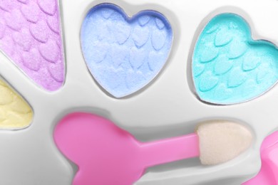 Photo of Decorative cosmetics for kids. Eye shadow palette with applicator as background, top view