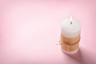 Pillar wax candle burning on color background