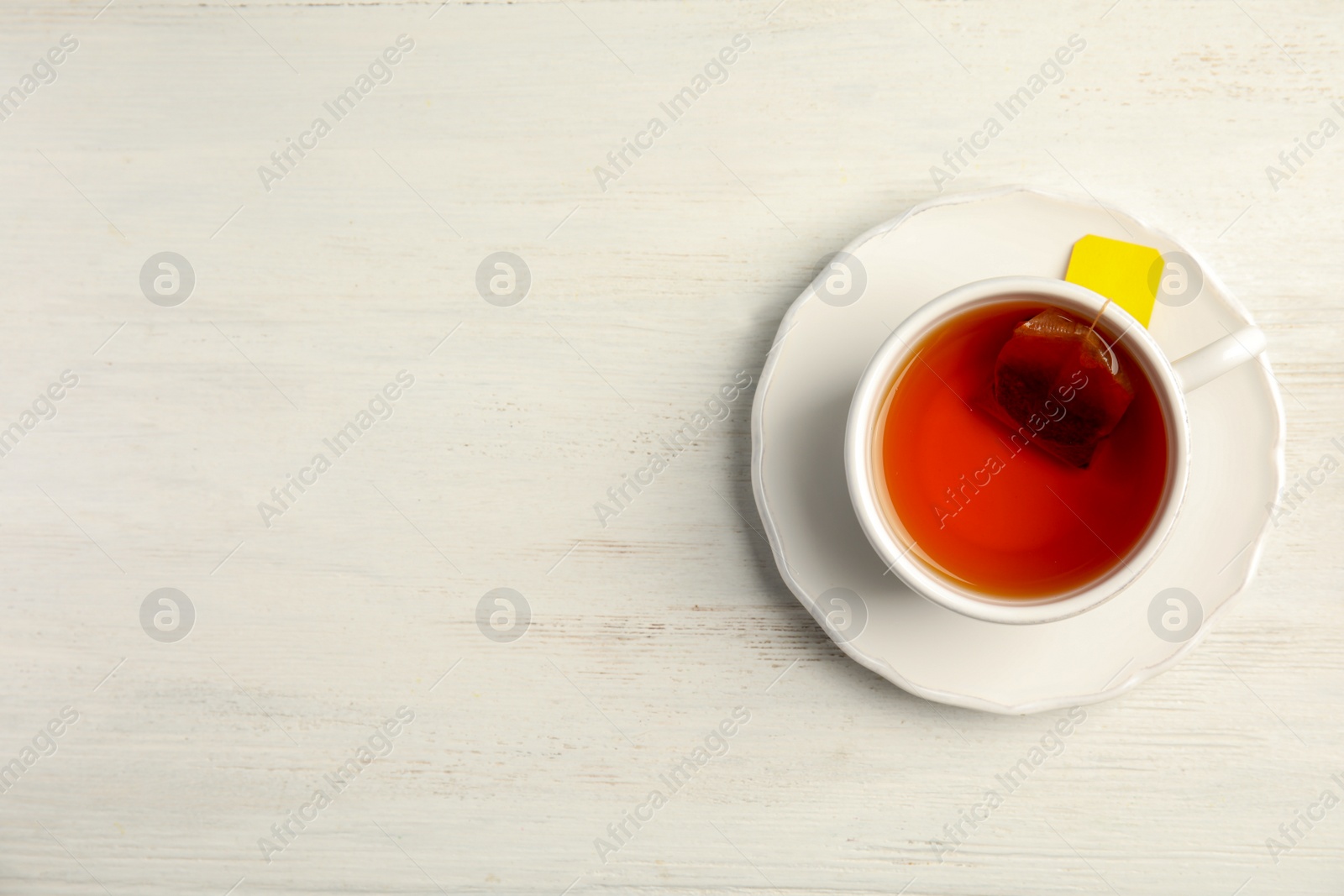 Photo of Cup of delicious tea with saucer on wooden background, top view