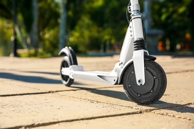 Modern electric kick scooter outdoors on sunny day, closeup
